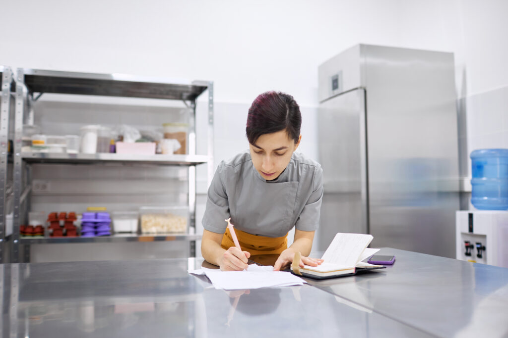 The pastry chef girl makes notes in a notebook