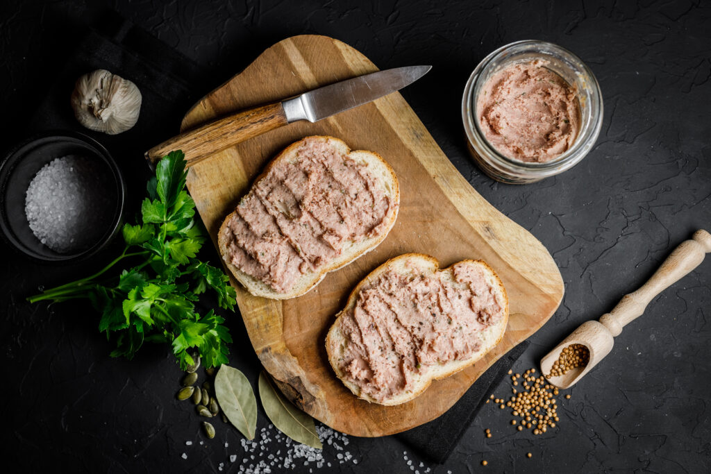 Liver pate with sandwiches pot en verre de terrine, mousse ou rillettes ainsi que le produit sur une baguette de pain.