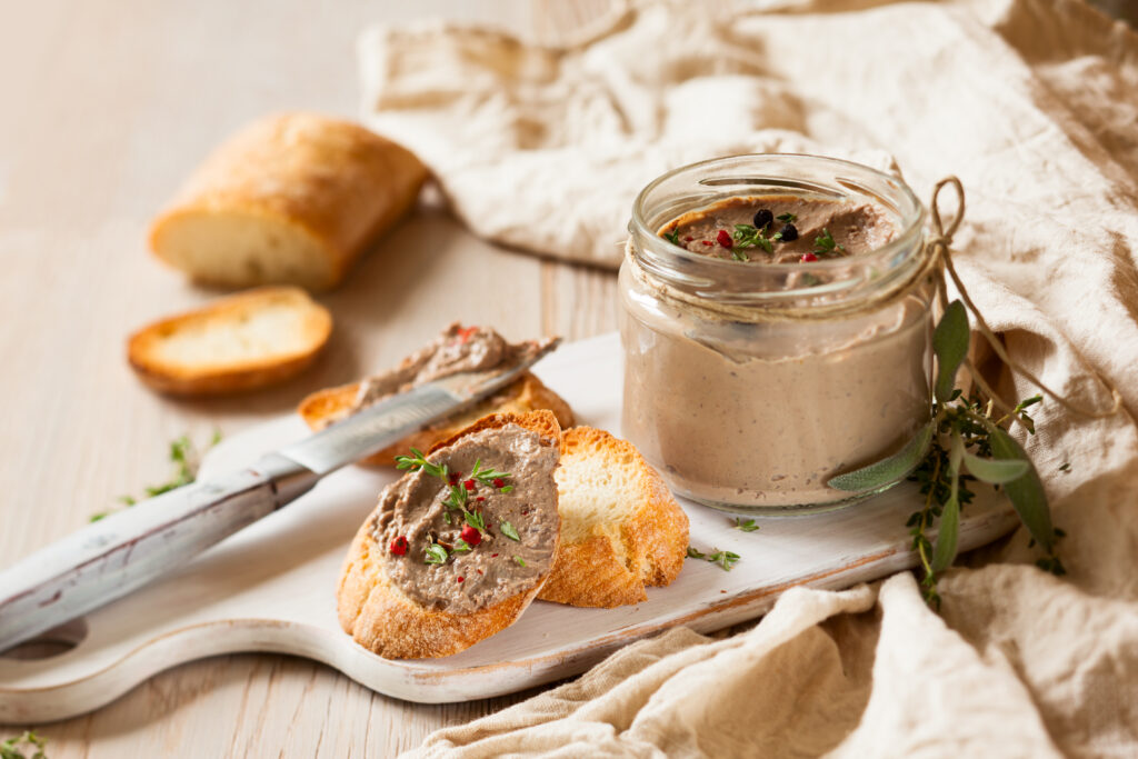pot en verre de terrine, mousse ou rillettes ainsi que le produit sur une baguette de pain.